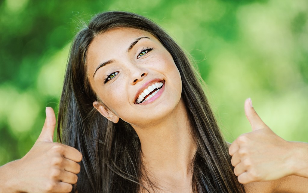 Woman with bare shoulders happily raises his thumb up